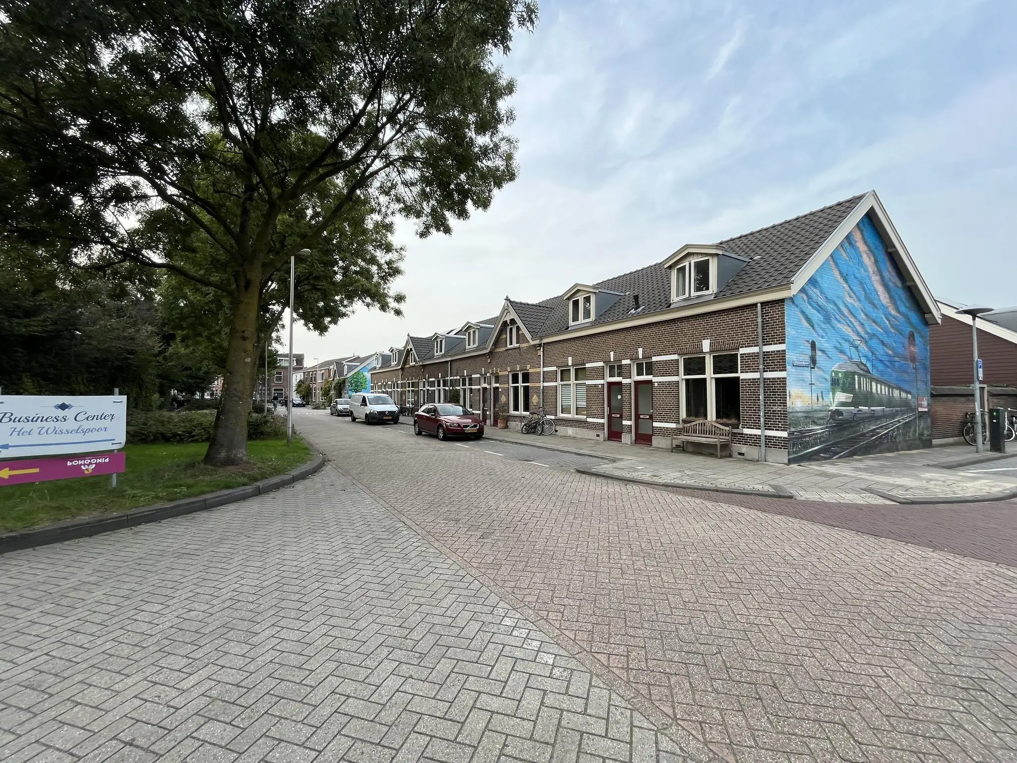 Straatbeeld van de 2e Daalsedijk met een muurschildering van een trein op een hoekhuis en een bord naar Business Center Het Wisselspoor.